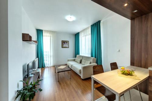 a living room with a table and a couch and a television at Belvedere Holiday Club in Bansko