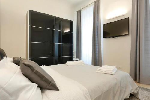 una camera con un grande letto bianco e una TV a schermo piatto di Opera 19 Luxury Apartment a Firenze
