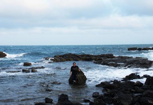 a man standing on a rock in the ocean at Dream Ocean View B&B in Magong