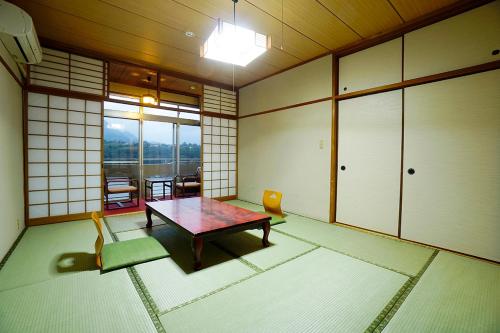 a room with a table and chairs in a room with windows at Hotel Yakushima Sanso in Yakushima