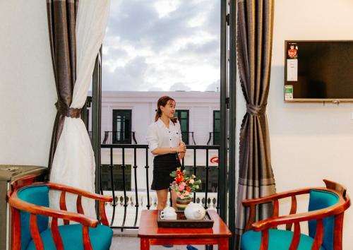 a woman standing on a balcony with two chairs at Tre Việt Tuy Hòa Hotel in Tuy Hoa