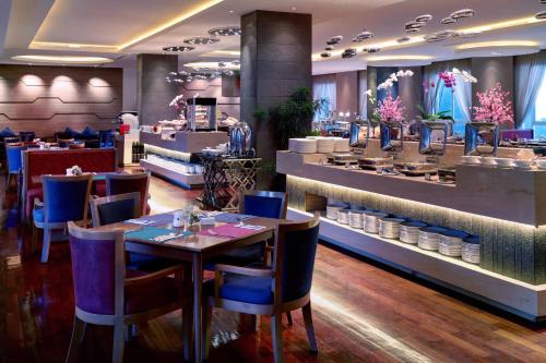 a restaurant with tables and chairs and a counter at Grand Mercure Bandung Setiabudi in Bandung