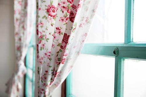a window with a curtain with flowers on it at 履舍民宿Footinn in Taitung City