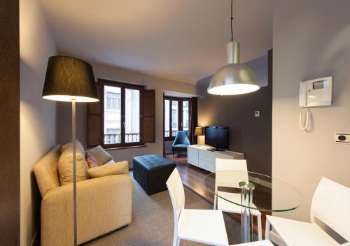 un soggiorno con divano e tavolo in vetro di MyHouseSpain - Apartamentos Moros 41 a Gijón