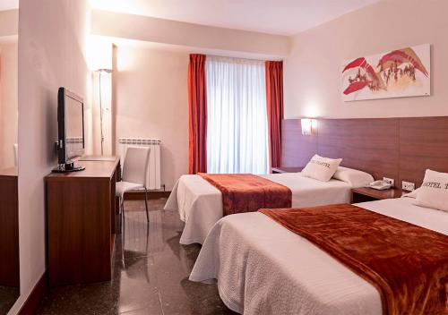 a hotel room with two beds and a flat screen tv at Hotel Txartel in Lasarte