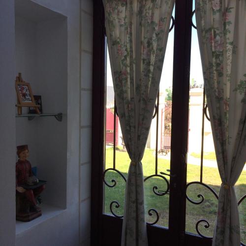 a window with curtains and a child looking out at the grass at LA VILLA BOLERO in Saint-Cyr-sur-Loire