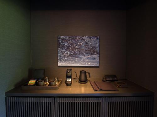 a room with a table with a telephone and a painting at barhotel Hakone Kazan in Hakone