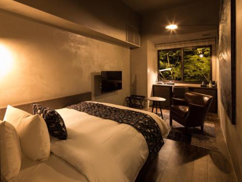 a bedroom with a bed and a desk and a window at barhotel Hakone Kazan in Hakone