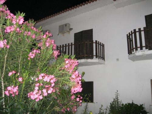 a white building with pink flowers and balconies at Residencial Morgado in Almeida