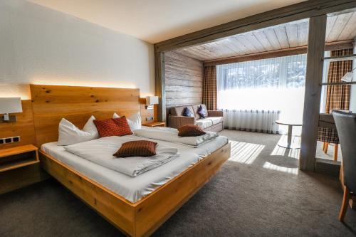a bedroom with a large bed and a large window at Hotel Quellenhof in Grainau