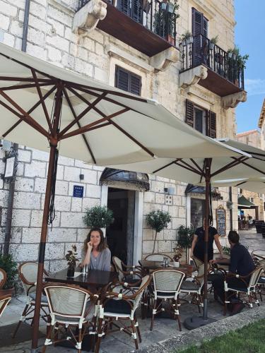 a woman sitting at a table under an umbrella at San Teodoro in Korčula