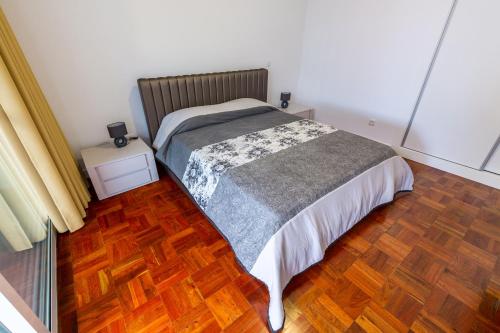 sypialnia z łóżkiem i drewnianą podłogą w obiekcie Sea Breeze II w Caniço