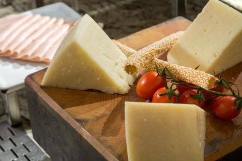 a block of cheese and tomatoes on a wooden cutting board at Porto Palace Hotel Thessaloniki in Thessaloniki