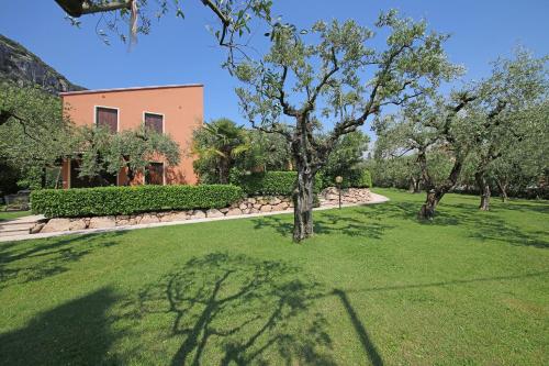 a garden with trees and a house in the background at Appartamenti Pratone in Garda