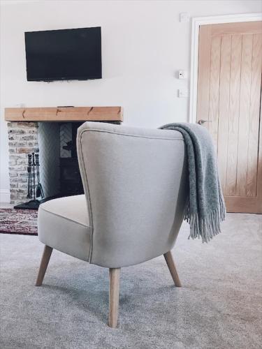 a chair with a blanket on the back of it in a living room at No.03 Cottage in Strathkinness