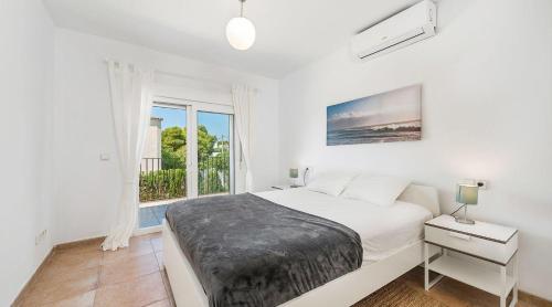 a white bedroom with a bed and a window at Torres de Cala Pi in Cala Pi