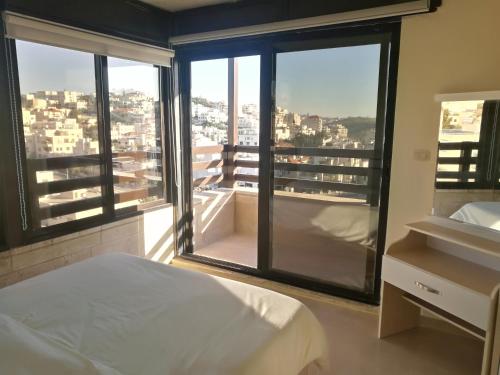a bedroom with a large window with a view of a city at Dair Ghbar Gate Apartments in Amman