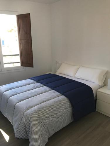 Una cama en un dormitorio con una manta azul. en Apartament L'Alba, en Tossa de Mar