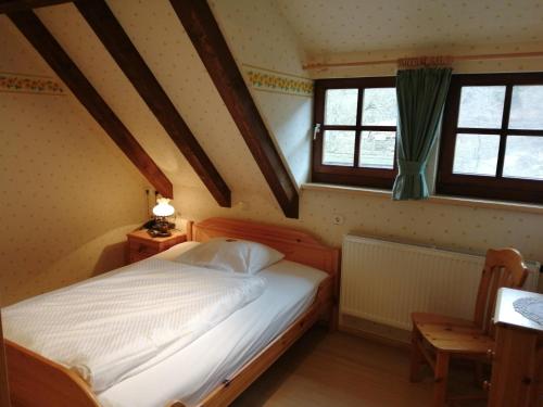 a bedroom with a bed and two windows at Der Lautenbachhof in Bad Teinach-Zavelstein