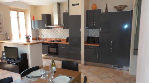 une cuisine avec des armoires noires et une table avec des chaises dans l'établissement spacieux logement face à la Cité Médievale, à Carcassonne