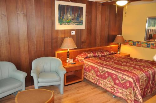 a hotel room with a bed and a chair at Le Boisé du Lac in Mont-Tremblant