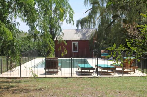 a fence with chairs and a pool in front of a house at Quinta El Monte in Tandil
