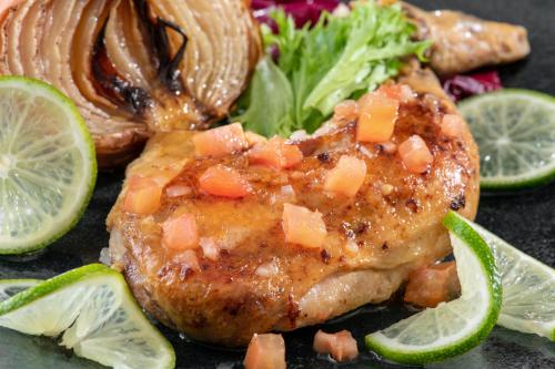 a piece of meat with salsa on a plate with a salad at Lime Resort Myoko in Myoko