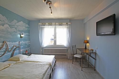 a bedroom with two beds and a television on the wall at Hotel Champ Alsace in Haguenau