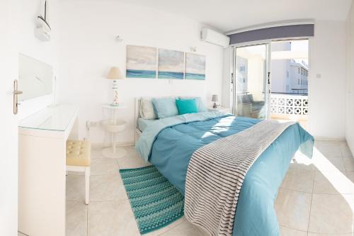 a white bedroom with a blue bed and a desk at Seaview 3 bedroom Kings Road Penthouse in Paphos