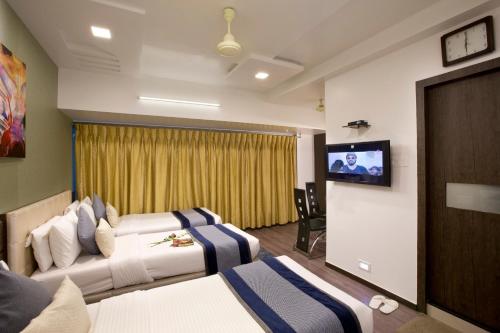 Habitación de hotel con 2 camas y TV de pantalla plana. en Hotel Planet Residency, en Bombay