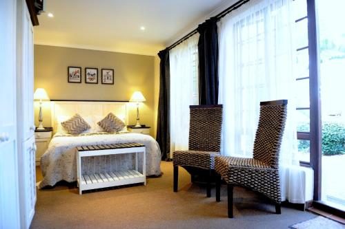 a bedroom with a bed and two chairs at Bayside Guesthouse in Port Elizabeth