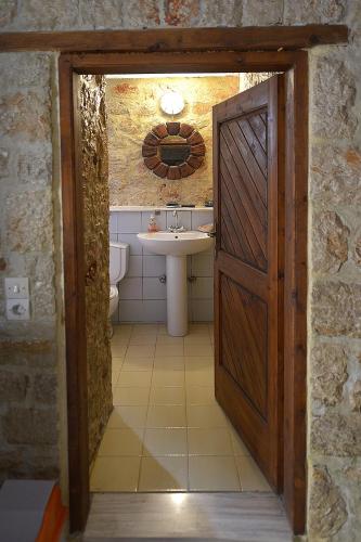 a bathroom with a sink and a wooden door at Rosalia Apartments in Halki