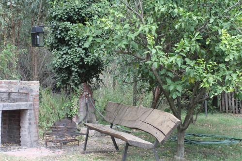 un banco de madera sentado bajo un árbol junto a una chimenea en Quinta El Monte en Tandil