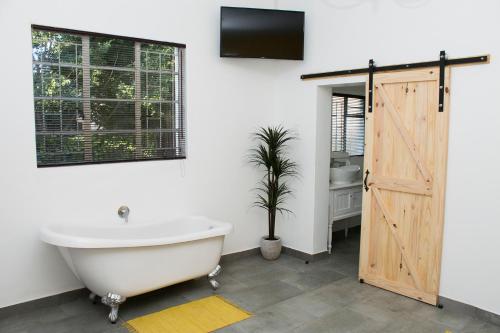 a bathroom with a bath tub and a sliding door at A Touch of Grace in Potchefstroom