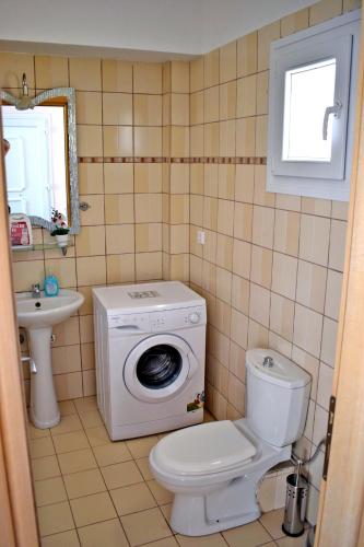 a bathroom with a toilet and a washing machine at Villa Lily in Skala Rachoniou