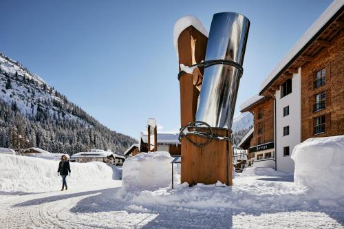 a woman standing in the snow next to a building at Hotel Auriga in Lech am Arlberg