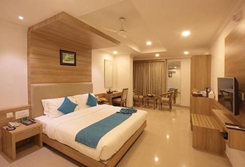 a hotel room with a bed and a dining room at Hotel Anjali Park in Kottayam