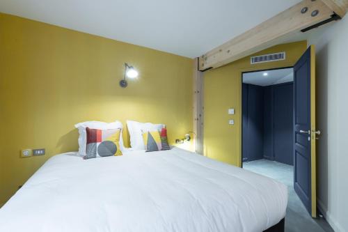 a bedroom with a large white bed with yellow walls at L'Abeille - Boutique Apartments in Nice