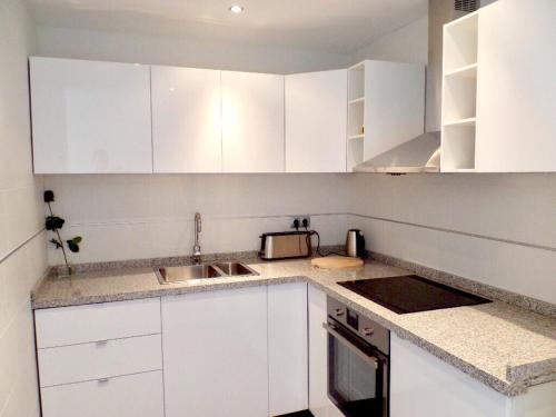 una cocina blanca con armarios blancos y fregadero en Villa Calle Montecillo, en Alhaurín el Grande