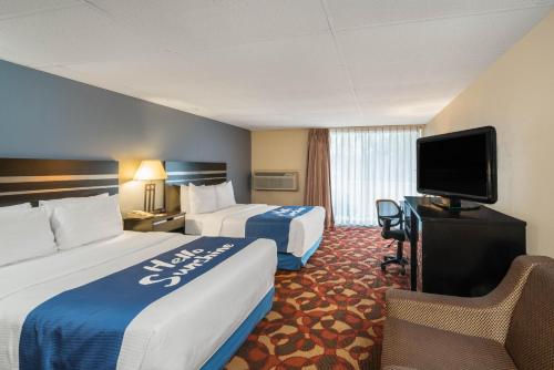 a hotel room with two beds and a flat screen tv at Days Inn By Wyndham Carlisle North in Carlisle