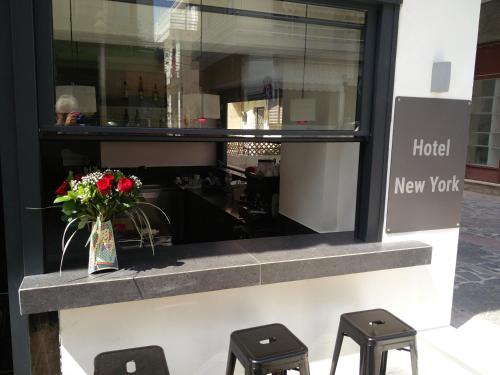 a store window with a vase of flowers and two stools at New York Hotel in Rhodes Town