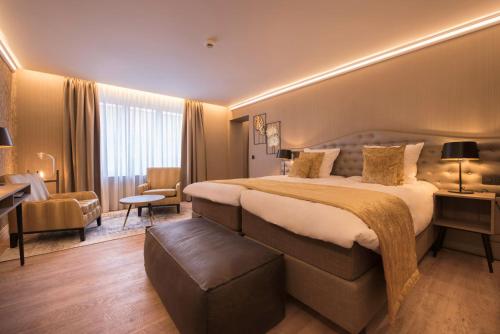 a hotel room with a large bed and a chair at Hotel Acacia in Bruges