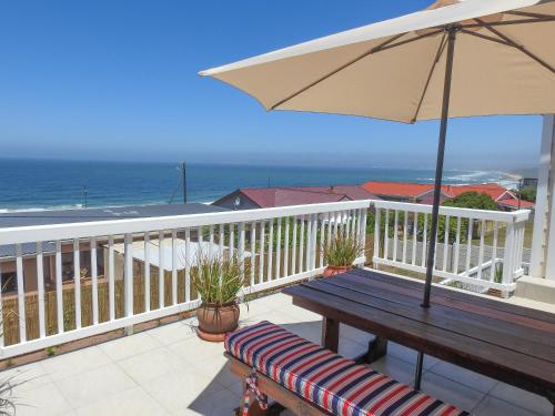 a wooden bench sitting on a balcony with an umbrella at Julsie's Home in Reebok