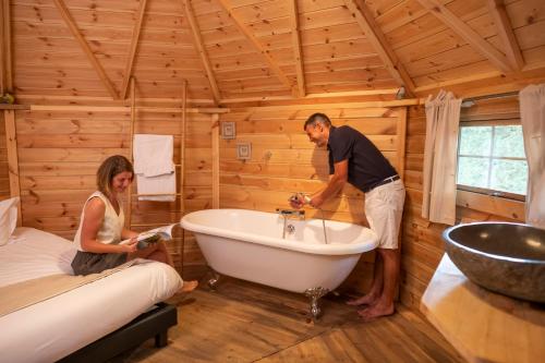 Ein Mann und eine Frau stehen in einem Badezimmer mit Badewanne in der Unterkunft Domaine De La Boulaie in Treize-Vents
