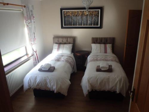 um quarto com duas camas com chapéus e toalhas em Torrent Cottage em Coalisland