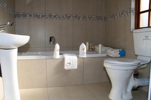 a bathroom with a toilet and a tub with towels at Classique Grace Boutique Hotel in Johannesburg