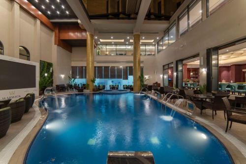 a large pool in a hotel with tables and chairs at Warwick Al Khobar in Al Khobar