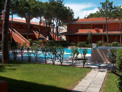 una piscina con mesa y árboles y un edificio en Villaggio Capistrano, en Bibione