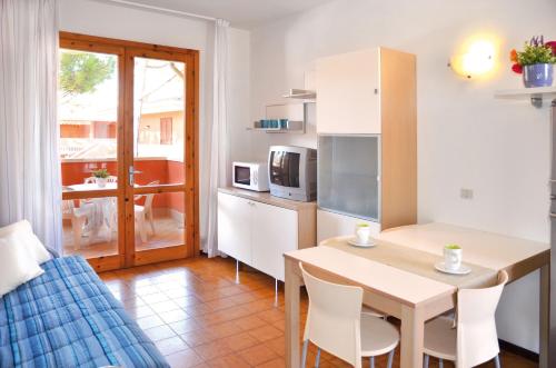 sala de estar con cocina, mesa y sillas en Villaggio Capistrano, en Bibione