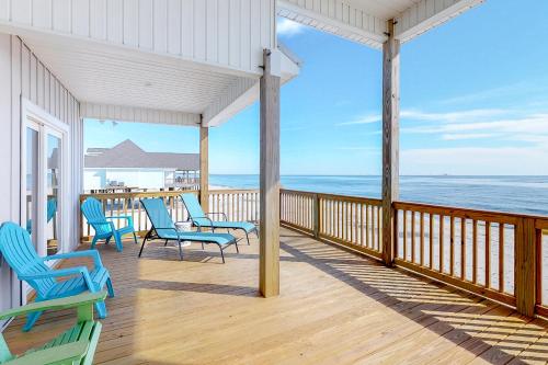 a porch with chairs and the ocean in the background at Waves of Grace in Dauphin Island